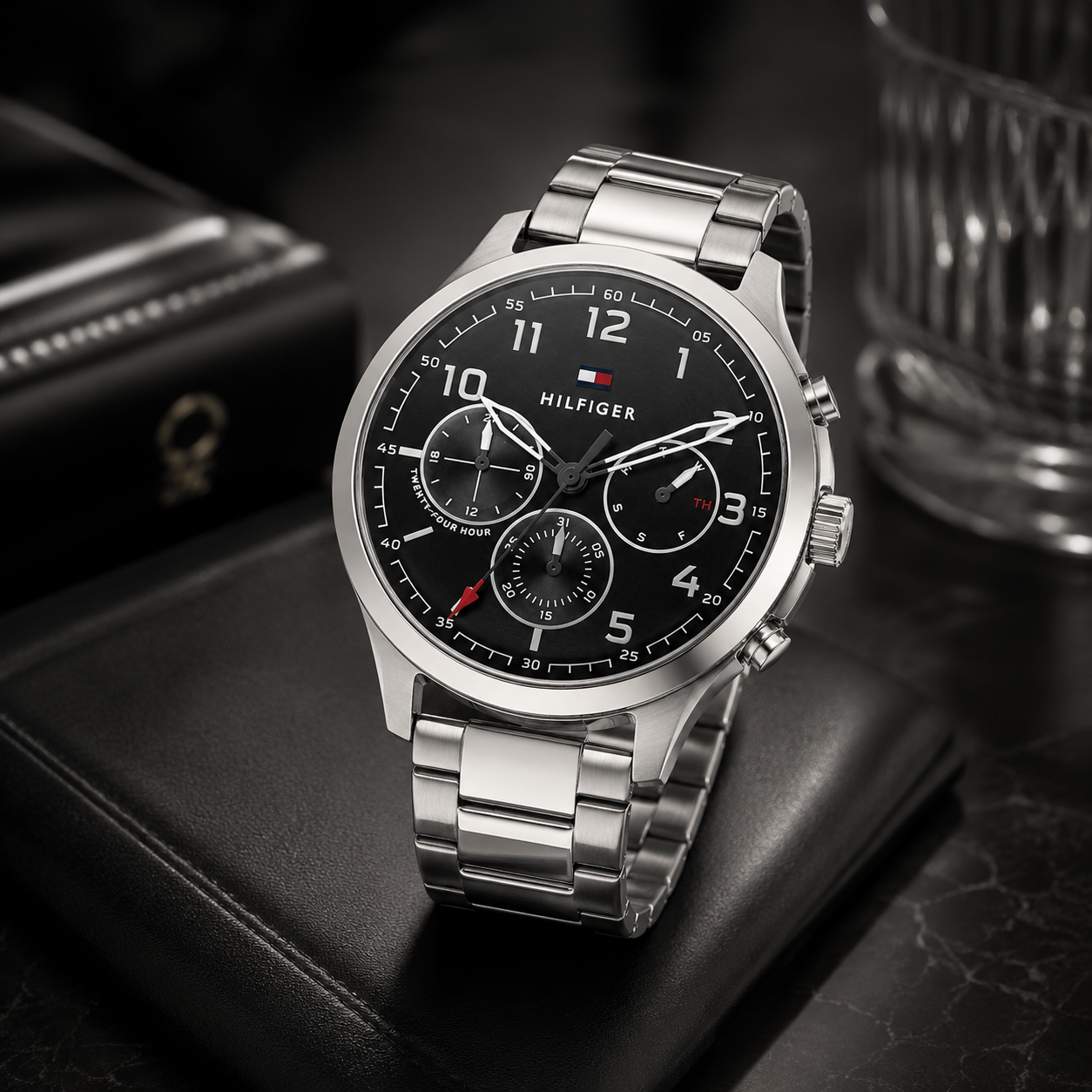 Reloj de hombre Tommy Hilfiger Asher 1791852 cronógrafo de acero inoxidable plateado sobre un cojín de cuero negro con esfera negra.